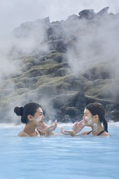 two women in a blue pool with steam rising from the water