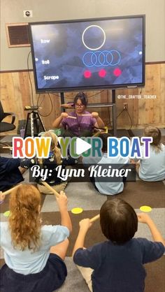 children sitting on the floor in front of a flat screen tv playing row your boat