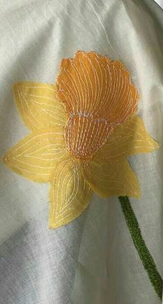 a yellow flower is sitting on a white cloth