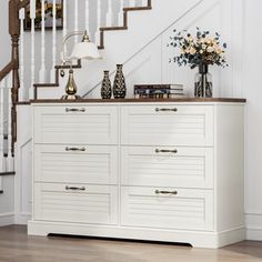 a white dresser sitting under a stair case