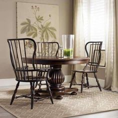 a dining room table with four chairs and a rug on the floor in front of it