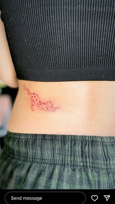 a woman's stomach with a small red tattoo on the lower part of her abdomen