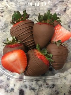 chocolate covered strawberries in a plastic container on a marble counter top, ready to be eaten