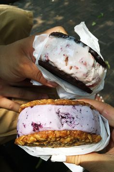 two people holding ice cream sandwiches in their hands