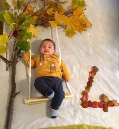 a baby laying on a swing next to a tree