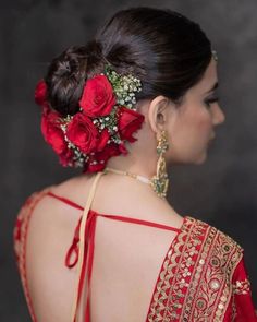 a woman wearing a red and gold sari with flowers in her hair, back view