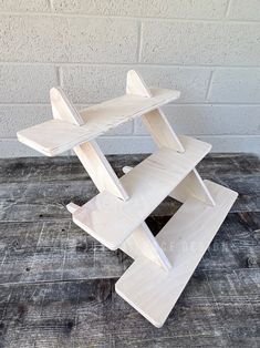 a wooden toy airplane sitting on top of a wooden table next to a brick wall