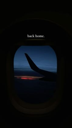 an airplane window with the words back home on it's side in front of a dark sky