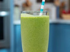 a green smoothie with a blue and white straw