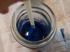 a blue liquid in a glass with a yellow straw sticking out of the top and bottom