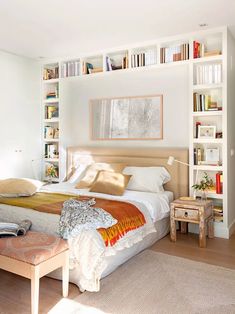 a bedroom with a bed, bookshelf and table in the corner next to it