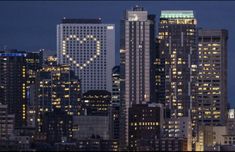 the city skyline is lit up at night, with skyscrapers in the foreground