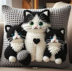 a crocheted pillow with three cats sitting on it's side and one cat holding the other