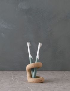 two toothbrushes in a holder made out of cork