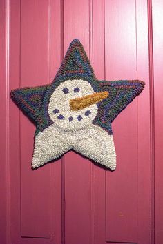 a snowman star hanging on the side of a pink door