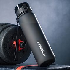 a black water bottle sitting on top of a luggage bag next to an exercise wheel