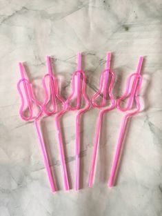 four pink plastic straws sitting on top of a marble counter