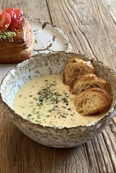 a bowl of soup with bread and strawberries in it on a wooden table top