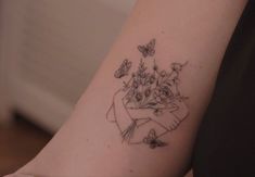 a woman's arm with a bouquet of flowers and butterflies tattooed on the wrist