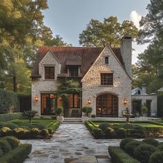 a stone house with lots of hedges and bushes around it's front entrance area