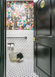 the bathroom is decorated in black and white with colorful flowers on the wall behind the door