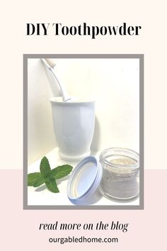 a white bowl filled with green leaves next to a cup full of powder and a spoon