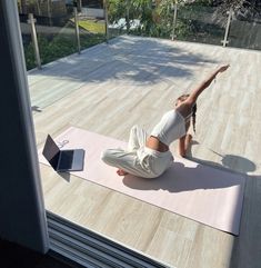 a woman is doing yoga on a mat outside with a laptop computer in front of her