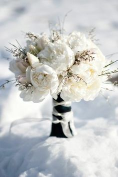 a bouquet of white flowers sitting in the middle of a snow covered ground with an ornate border around it