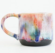 a colorful coffee mug sitting on top of a white table