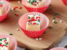 red and white cupcakes with sprinkles on a wooden cutting board