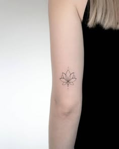 a woman's arm with a small flower tattoo on the back of her left arm