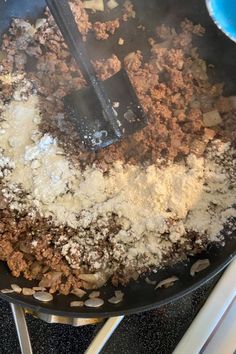 a frying pan filled with food and cooking utensils on top of a stove