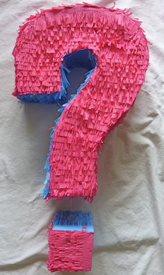 a pink and blue paper mache shaped like a question mark on top of a white sheet