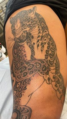 a woman's thigh with a tattoo on it that has a cat and snake on it