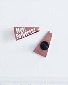 two pins with words on them sitting next to each other in front of a white wall