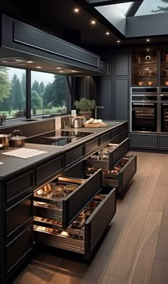 an open drawer in the middle of a kitchen with dark cabinets and wood flooring