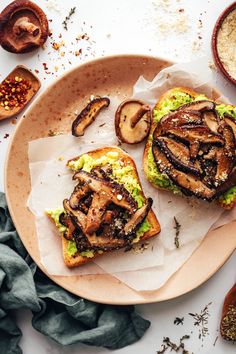 two sandwiches with mushrooms and avocado are on a plate