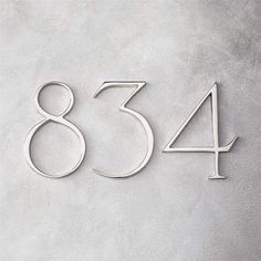 the number 854 is made out of metal and sits on a gray surface with a white background