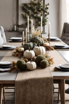 a dining room table decorated with white pumpkins and greenery