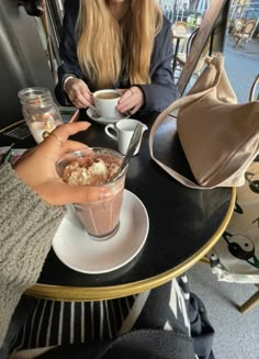 a woman sitting at a table with a cup of coffee