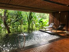 an indoor hot tub in the middle of a wood floored area with chairs and plants