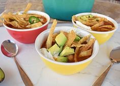 three bowls filled with food sitting on top of a table next to utensils