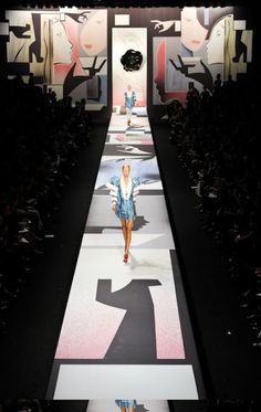 a woman walking down a runway at a fashion show