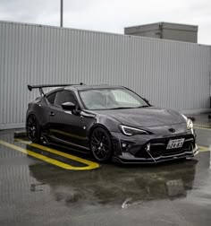 a black sports car parked in a parking lot next to a white building with yellow lines