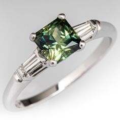 a green diamond ring with three baguets on it