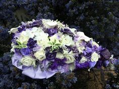 a bouquet of purple and white flowers is laying on the ground next to some bushes