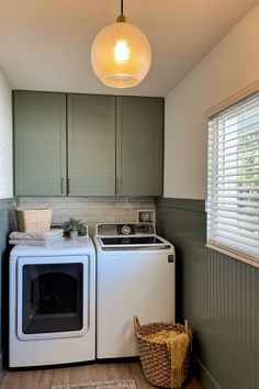 a washer and dryer in a small room with green walls, wood flooring and gray cabinets