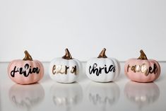 three painted pumpkins sitting on top of a white table next to each other with the word autumn written on them