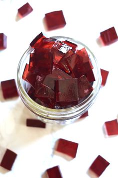 a glass jar filled with red cubes on top of a table