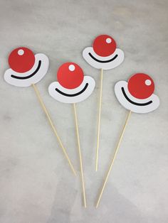 four red and white cupcake top picks with smiley faces on them, sitting next to each other